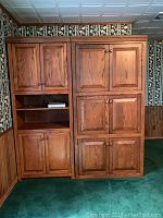 Front view of large solid oak entertainment center with multiple paneled cabinet doors and open shelves on the left side.