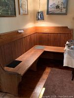 Corner oak church pew bench situated in room corner beneath framed art, showing slate inlays on the seat and wooden paneled backrest.