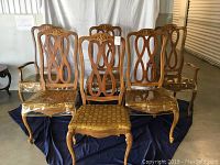 Front view of six dining chairs including two armchairs and four side chairs arranged on a dark cloth backdrop.