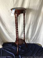 Full view of two-tiered wood plant stand showing rope-style twisted legs and round shelves