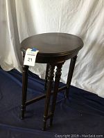 Round top wooden table with turned legs shown.