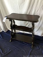 Front and top angled view of the dark wooden magazine table with two bottom shelves, showing the table design and condition.