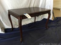 Front view of the wooden end table showing carved apron and legs