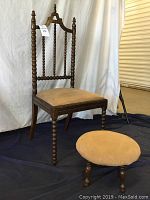 Side view of the vintage accent chair showing spindle detailing and matching ottoman in front.