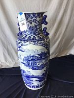 Full view of the Chinese blue and white porcelain vase showing the traditional landscape painting and decorative neck.