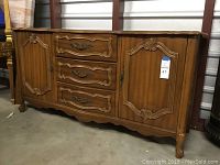 Front view of the French Provincial buffet showing the drawers and side cabinets with ornate carved wood and metal hardware.