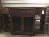 Full front view of the vintage wooden buffet showing front drawers, woven metal panel cabinet doors, and open side shelves with glass backing.