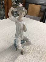 Porcelain figurine visible from front view, showing the girl holding a hairbrush in her right hand.