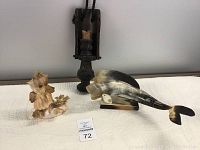 Lot showing shell figure, bull horn shark figure, and wooden sconce on white quilted surface.