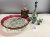 Full view of all items showing multicolored decanter, Jeannie bottle decanter with four glasses, and large bowl