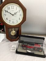 Westminster Chime Quartz pendulum wall clock with wooden frame and the Mercedes Benz 770K model car in a display case on a white surface.