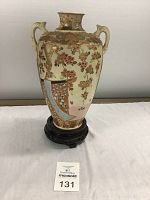 Front view of the vase showing floral and gold painted motifs and upright handles.