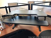 Ergonomic office desk with a curved work surface and black keyboard tray on metal legs.
