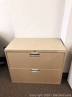 Beige 2 drawer filing cabinet with metal handles, showing front view.