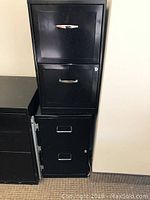 Black 4-drawer metal filing cabinet with visible upper and lower drawers and silver handles, used office furniture.
