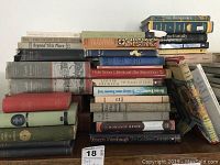 Stack of various literature and fiction books including titles like 'The Heart of Music,' 'Beyond This Place,' 'In Great Tradition,' and 'Joseph Wambaugh: The Golden Orange.' Books are mostly hardcover and varying sizes.