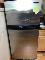 Front view of KitchenAid stainless steel refrigerator showing two doors with black handles and KitchenAid brand badge on top door.