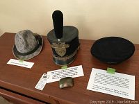 Group photo showing the three hats arranged on a wooden surface with descriptive labels.
