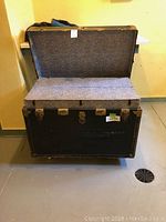 Open vintage steamer trunk showing overall condition, exterior dark color with metal corners and latches.