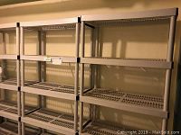 Four beige plastic shelving units lined up side by side against a wall.
