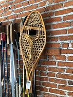 Photo of one snowshoe hanging on a brick wall in vertical position showing overall condition and shape