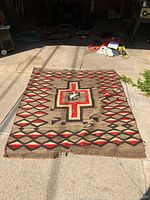 Full view of the Navajo blanket laid out flat, showing overall geometric pattern and central cross design.