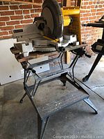 Side view of the Dewalt DW705 compound miter saw on a Rock Island Workmate stand, showing the full setup and condition.