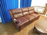 Brown leather Sklar Pepplar couch with three back cushions, rounded arms with brass nailhead trim, showing wear and damage.