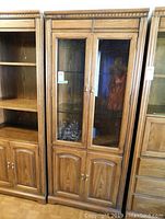 Front view of the wooden wall unit cabinet with glass doors and bottom storage compartments.