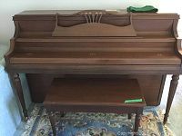 Front view of Willis and Co upright piano with closed lid and bench in front.