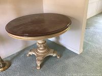 Full round dining table showing the wood top and painted pedestal base.