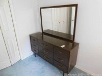 Full view of dark wood 9-drawer dresser with attached rectangular mirror from mid-century modern era