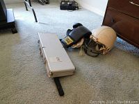 Lot including Riddell football helmet, Everlast boxing gloves, elbow pads, tensor bar and metal poker set case on carpeted floor