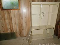 Photo of the assembled melamine wall unit without doors in a basement room with wood panel walls.
