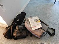 Three soft carrying bags including one open with Kodak EasyShare digital camera and accessories inside, plus an Image brand tripod in its carry case