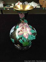 Front view of cloisonné vase showing pink flower and green leaves on a black background with gold detailing