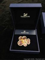 Brooch inside open navy blue Swarovski box, showing entire flower shape and setting