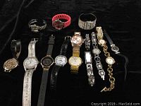 Lot of 15 assorted quartz wristwatches in various styles and bands, displayed on black background.