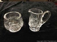 Photo showing the crystal sugar bowl and creamer pitcher side by side on a black surface.