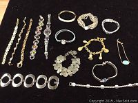 Top view of the 15 costume jewelry pieces laid out on black surface showcasing varied bracelet and necklace styles.