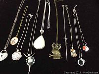 Photo showing all 10 necklaces arranged on black background, visible various pendant shapes and chain styles