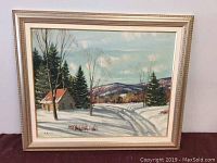 Framed oil painting showing full winter landscape scene including cabin, trees, and mountains.