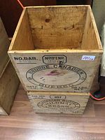 Photo showing inside of two stacked wooden butter boxes with 'Beurre Canadien Quebec' marking on the top box and 'Canadian Butter Mildmay Brand' marking on the bottom box.