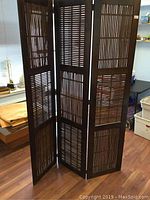Front view of the three-panel folding divider screen showing the bamboo slat design and dark wood frame.