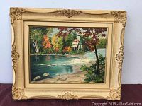 Full view of framed oil painting depicting a river, trees with autumn foliage, and a house, measuring approximately 22.5 by 18.5 inches.