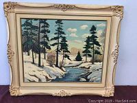 Full view of framed oil painting of winter landscape with pine trees and stream