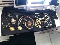 Photo showing the full assortment of vintage costume jewelry on a black cloth, including cameo, agate, beads, chains, and earrings.