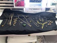Multiple necklaces, pendants and earrings laid out on black cloth