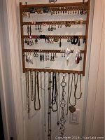 Full view of rack holding multiple rows of earrings and necklaces hung on bottom row.
