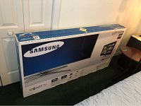 TV in original sealed box leaning against wall